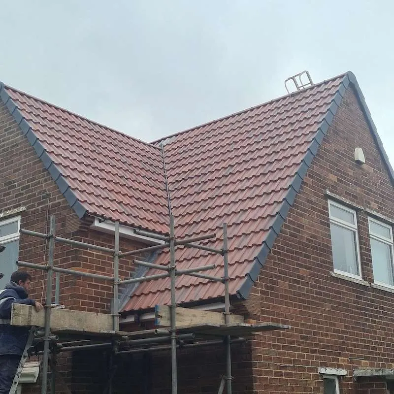 Skilled roofer installing tiles on a residential roof in Leicestershire using professional tools